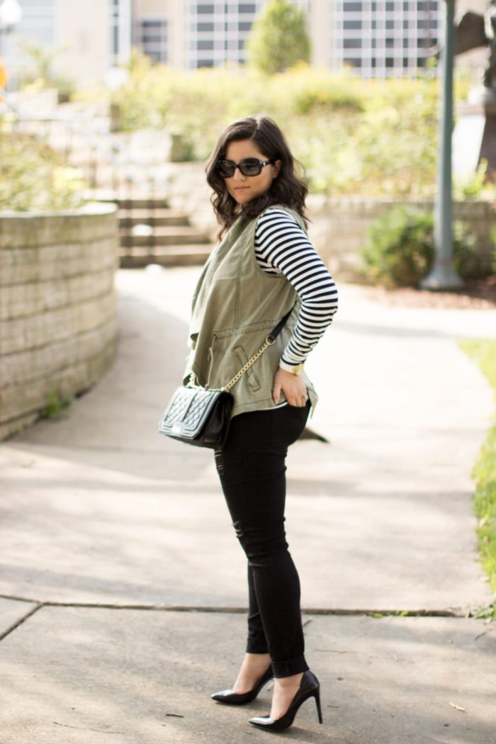 how to style a green utility vest, striped top, black skinny jeans, distressed black jeans, black quilted crossbody handbag, fall outfit idea, casual fall outfit